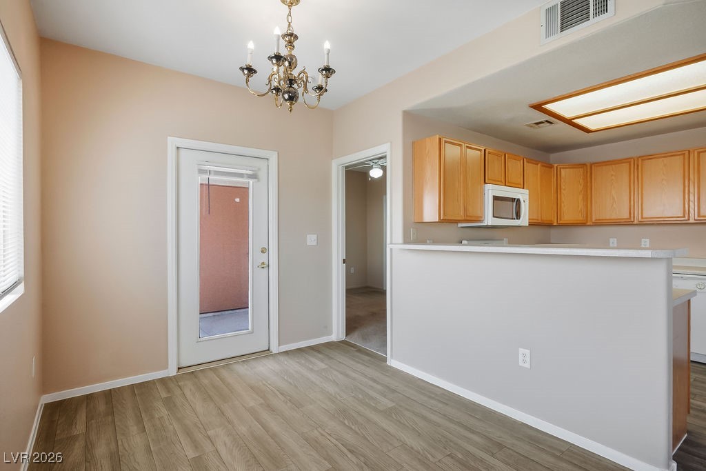 4655 Gold Dust Avenue, Unit 211 Las Vegas, NV 89120 - Photo 7 of 24 Kitchen with light countertops, a chandelier, light wood-style flooring, decorative light fixtures, and white appliances