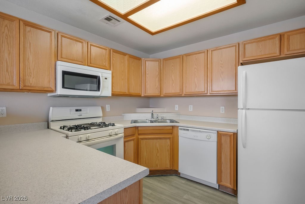 4655 Gold Dust Avenue, Unit 211 Las Vegas, NV 89120 - Photo 8 of 24 Kitchen with white appliances, light countertops, and light wood-style flooring
