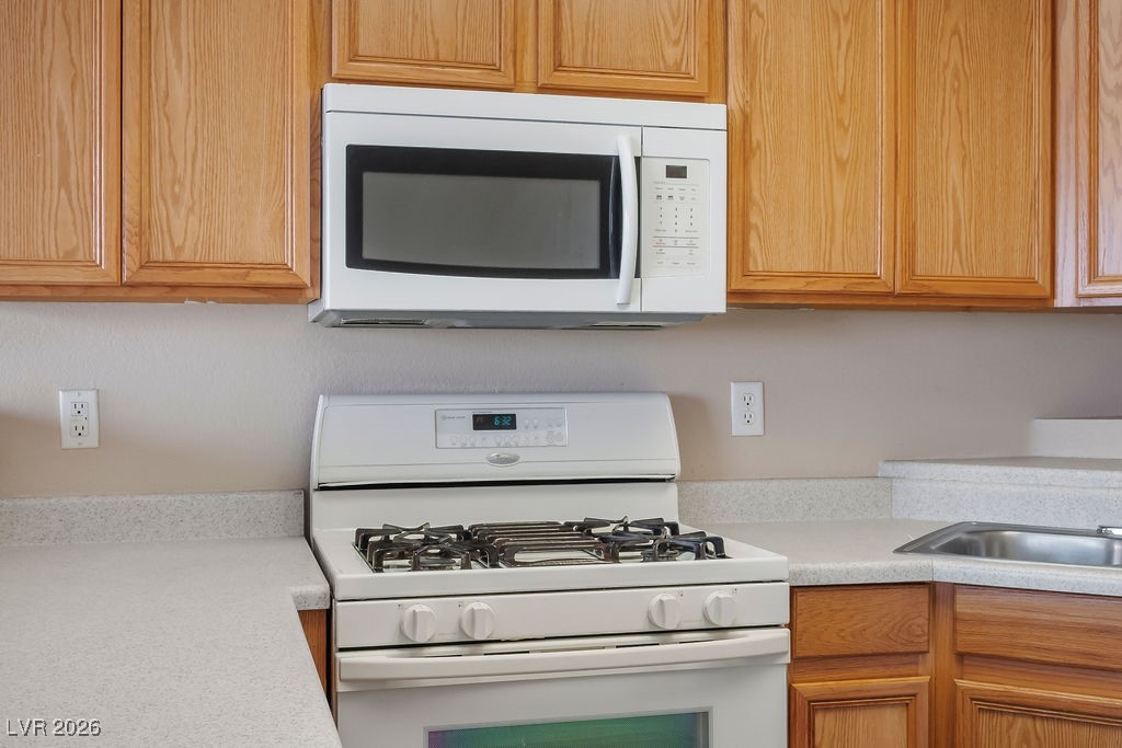 4655 Gold Dust Avenue, Unit 211 Las Vegas, NV 89120 - Photo 10 of 24 Kitchen featuring white appliances and brown cabinetry