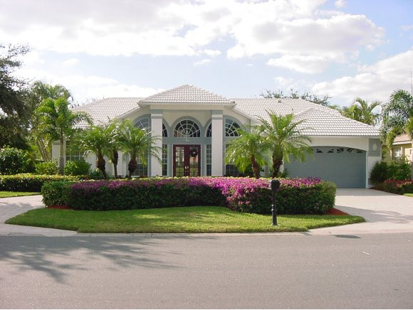 8949 Lely Island Circle Naples, FL 34113 - Photo 10 of 11 a front view of a house with a garden and garage