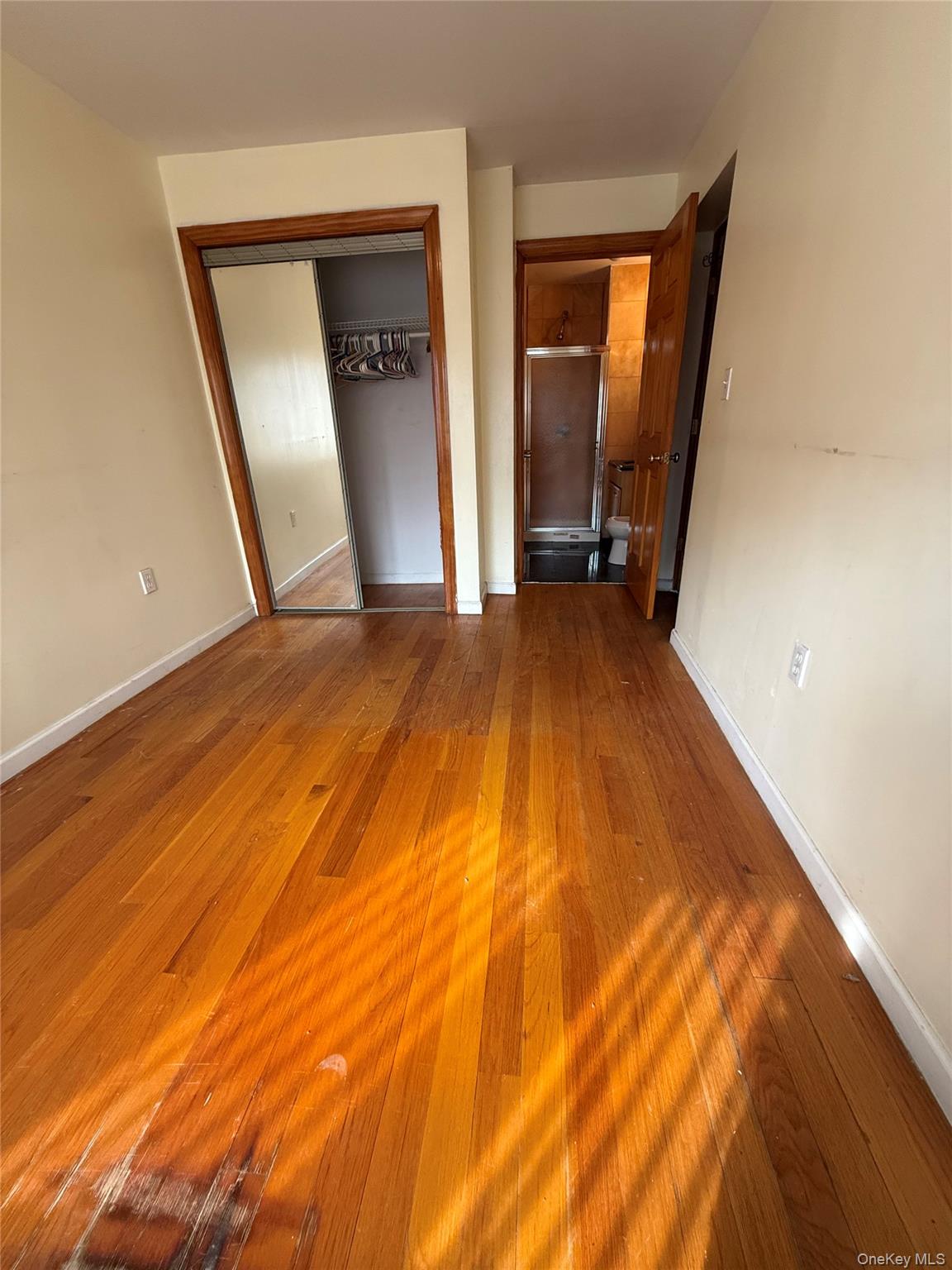 112-31 38th Avenue, Unit 3D Queens, NY 11368 - Photo 4 of 8 a view of an empty room with wooden floor and a window