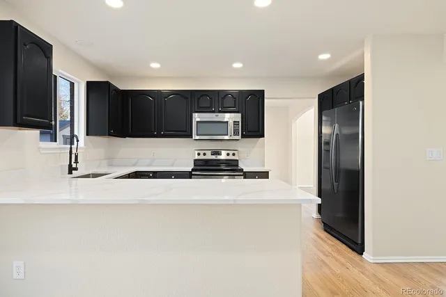 a large kitchen with stainless steel appliances a refrigerator a stove top oven a sink and dishwasher