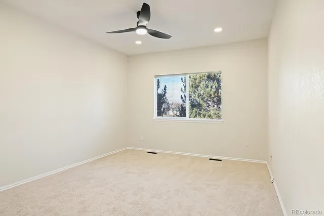 an empty room with a ceiling fan and window