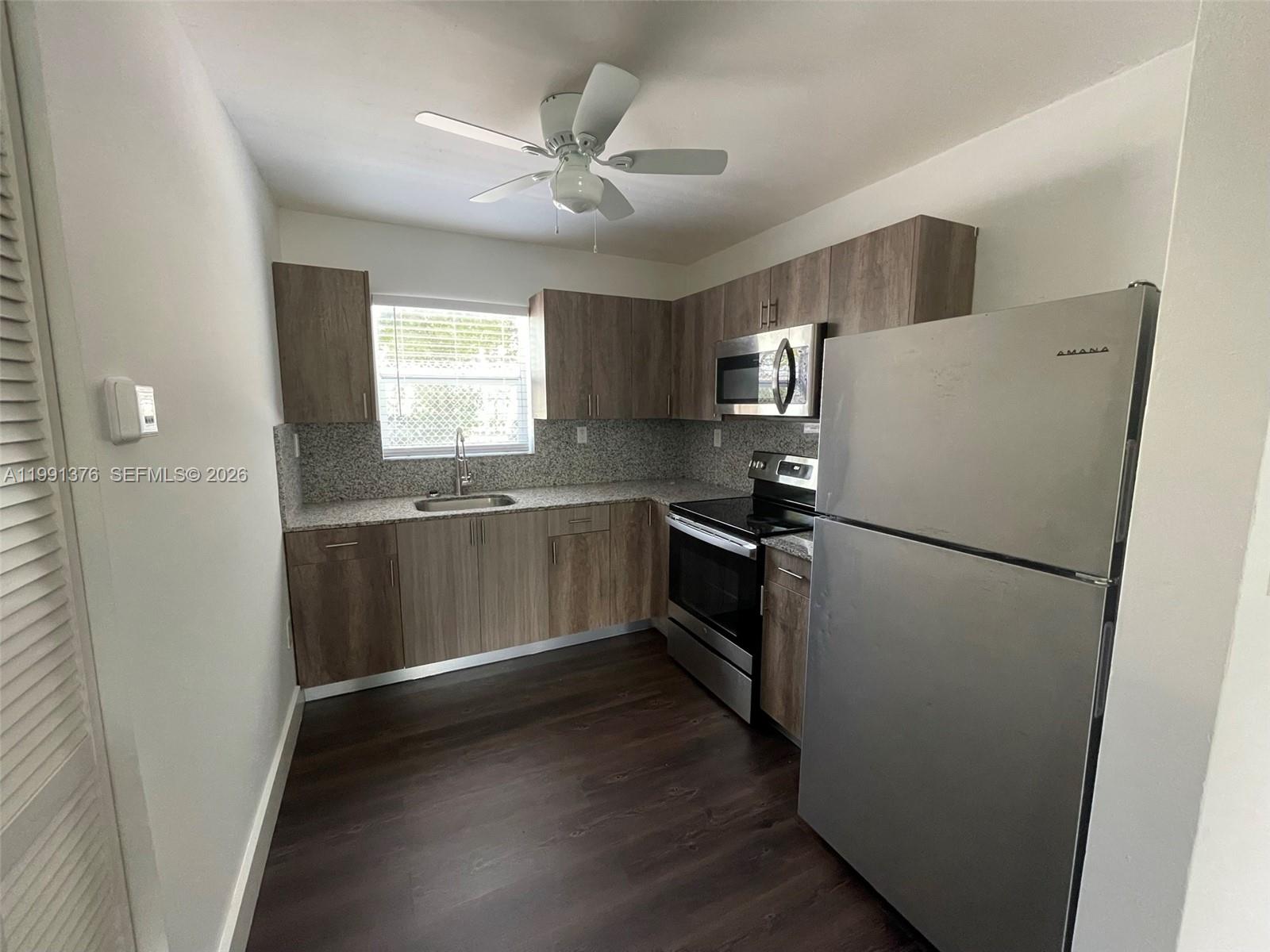 1864 Northwest 24th Street, Unit 4 Miami, FL 33142 - Photo 2 of 6 a kitchen with a refrigerator sink and cabinets