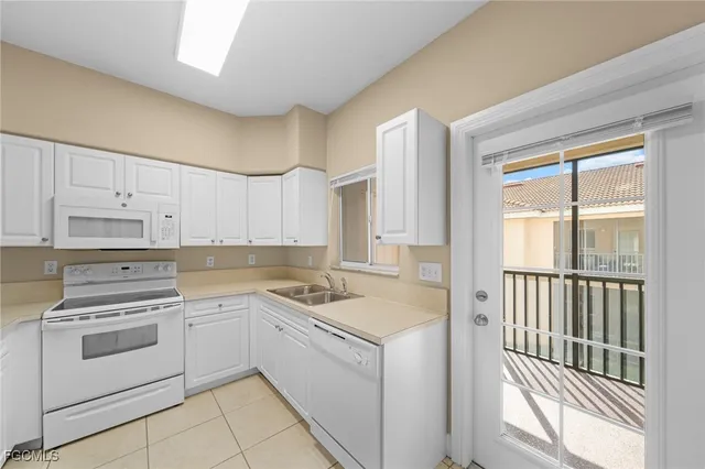 a kitchen with white cabinets appliances and a window