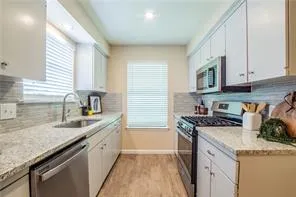a kitchen with granite countertop a sink a stove and cabinets