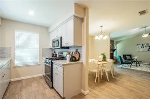 a kitchen with stainless steel appliances granite countertop a stove top oven a sink a dining table and chairs with wooden floor