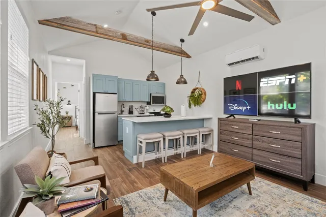 a living room with furniture a flat screen tv and a refrigerator