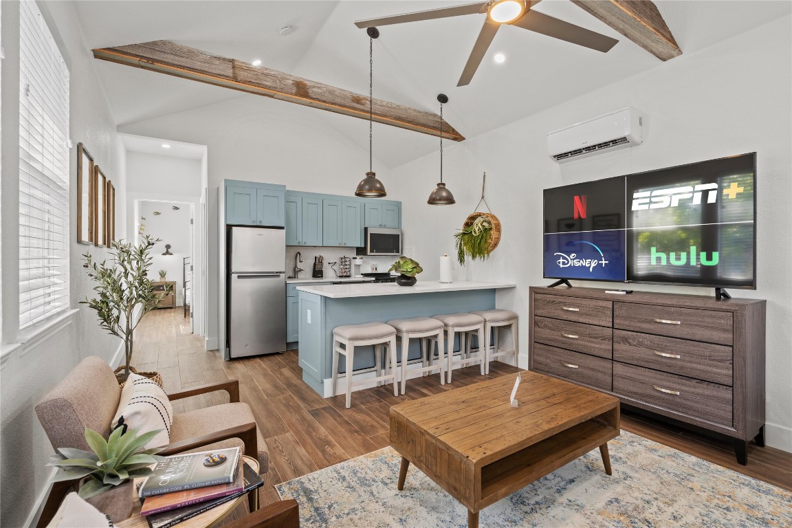 a living room with furniture a flat screen tv and a refrigerator
