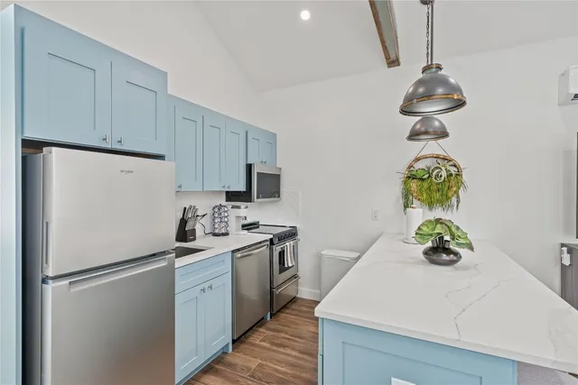 a kitchen with stainless steel appliances a sink a refrigerator cabinets and wooden floor