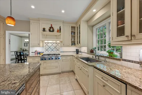 a large kitchen with granite countertop a sink and white cabinets