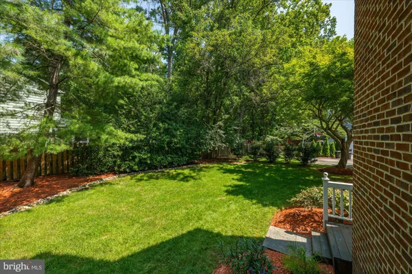 a view of a house with a big yard and large trees
