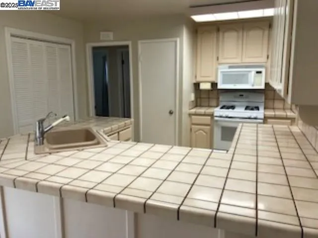 a kitchen view with a stove a sink and a refrigerator