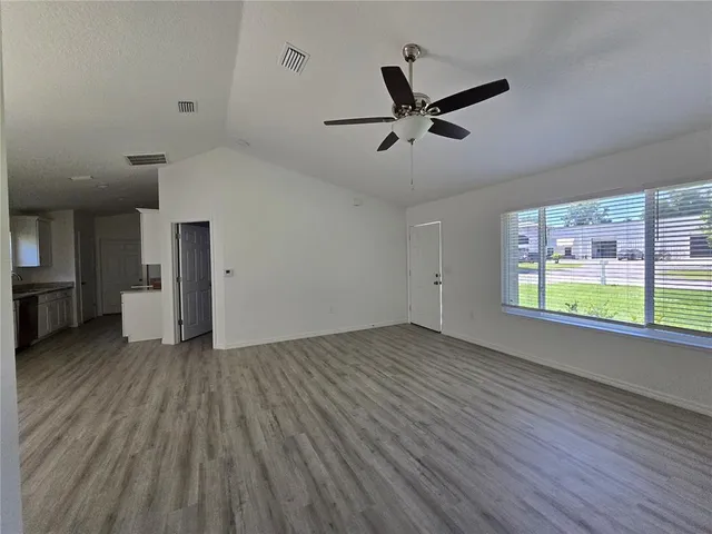 a view of empty room with wooden floor and window
