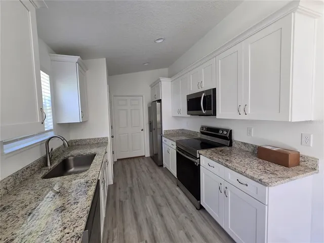 a kitchen with a sink stove top oven and microwave