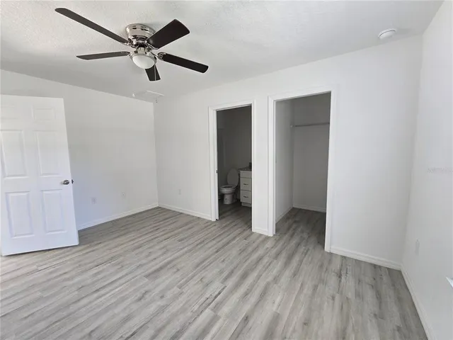 an empty room with wooden floor ceiling fan and window
