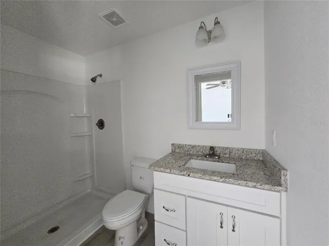 a bathroom with a granite countertop sink a toilet and shower