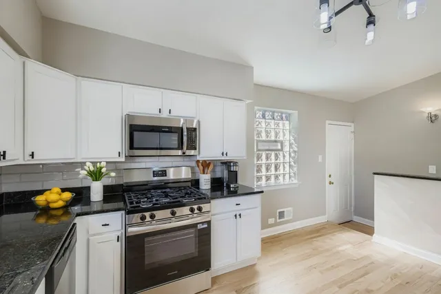 a kitchen with stainless steel appliances granite countertop a stove a sink and a white cabinets