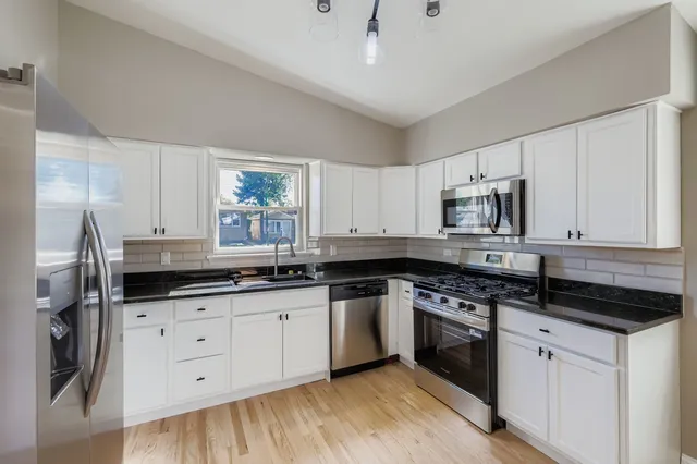 a kitchen with granite countertop a sink cabinets and stainless steel appliances