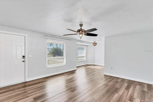 a view of an empty room with wooden floor and a window