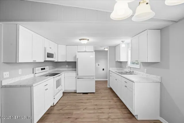 a kitchen with a refrigerator a sink dishwasher a stove and white cabinets with wooden floor