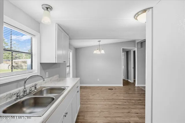 an empty room with chandelier fan and windows