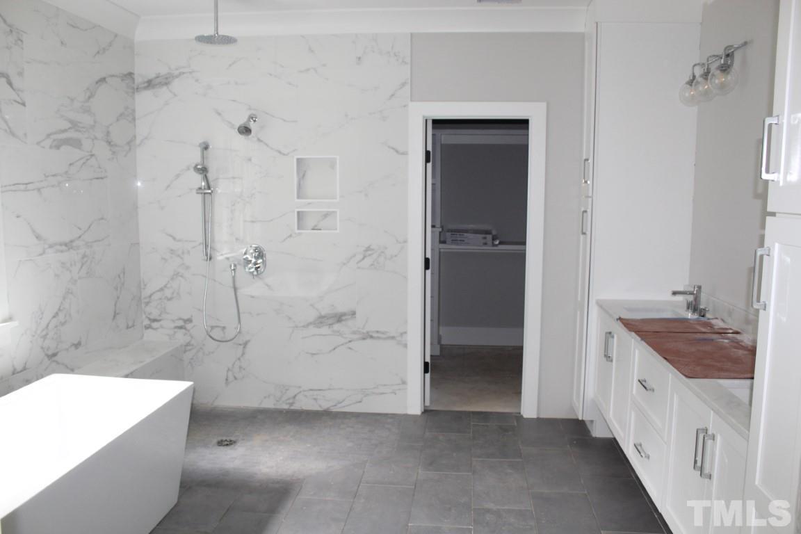 2309 Sanctuary Drive Raleigh, NC 27606 - Photo 8 of 22 a bathroom with a tub a sink a vanity and a shower