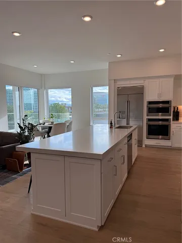 a large kitchen with stainless steel appliances a large counter top a stove and a sink