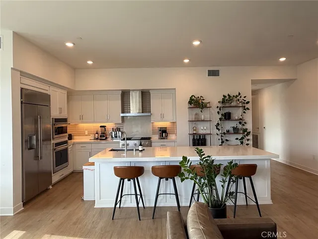 a kitchen with stainless steel appliances a dining table chairs refrigerator and sink