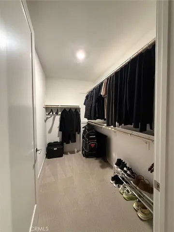 a view of walk in closet with clothes and shoes