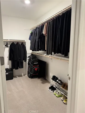 a view of walk in closet with clothes and shoes