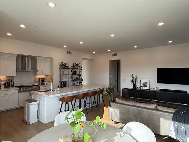 a kitchen with stainless steel appliances a dining table chairs and a refrigerator