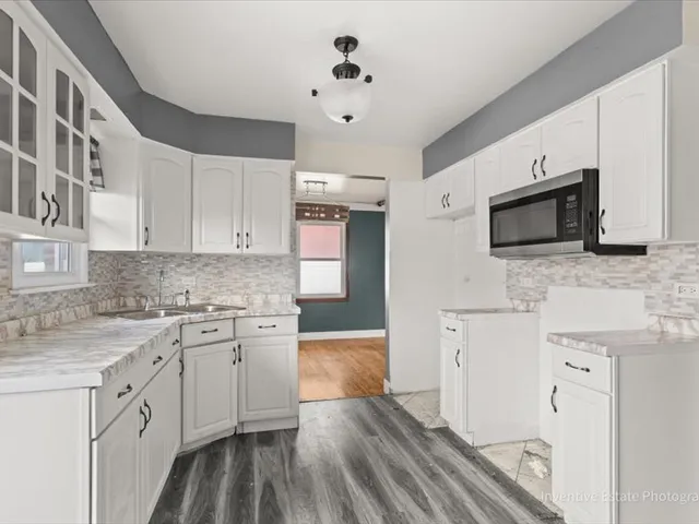 a kitchen with granite countertop a sink stainless steel appliances and white cabinets