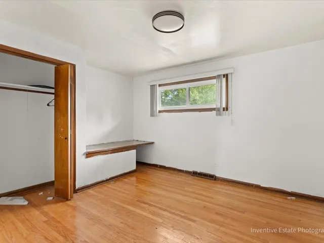 an empty room with wooden floor and window