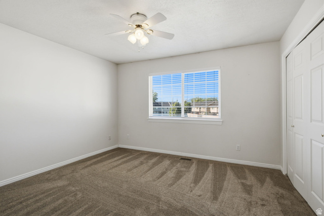 794 East 950 S Street Provo, UT 84606 - Photo 21 of 28 Spacious room featuring neutral carpeting, a large window, white trim, a ceiling fan with light fixture, and a bi-fold closet door