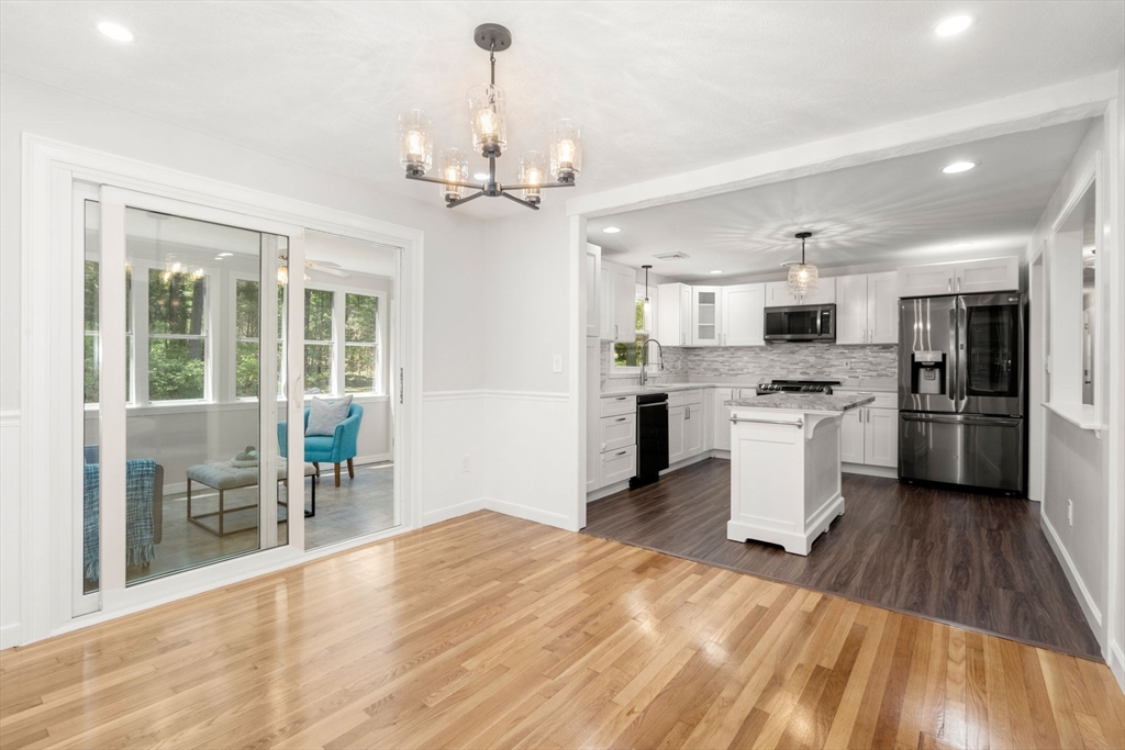 98 Union Street Norfolk, MA 02056 - Photo 7 of 38 a large white kitchen with granite countertop a stove top oven a sink dishwasher a dining table and chairs with wooden floor