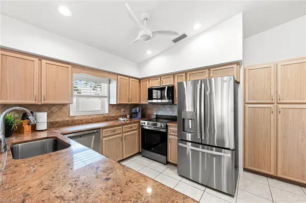 a kitchen with stainless steel appliances granite countertop a refrigerator a sink dishwasher a stove with white cabinets