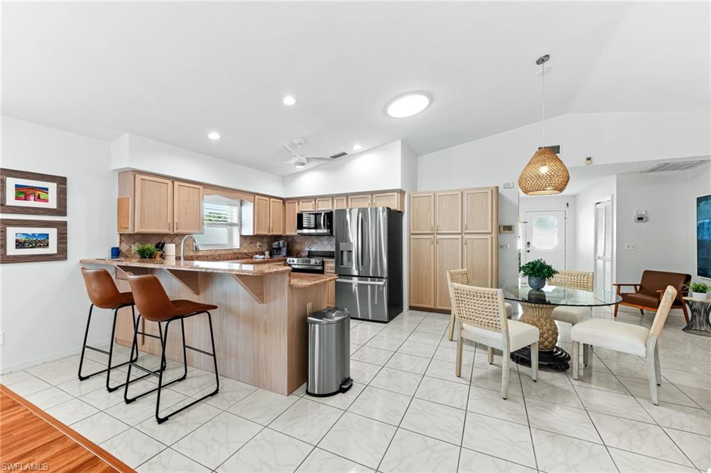 690 100th Avenue North Naples, FL 34108 - Photo 12 of 33 a kitchen with stainless steel appliances kitchen island granite countertop a refrigerator and a dining table