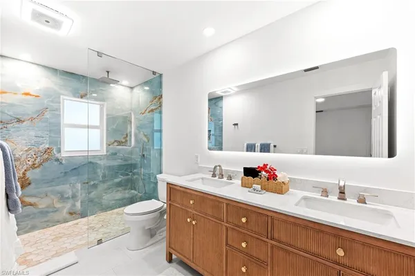 a bathroom with a granite countertop sink mirror vanity and toilet