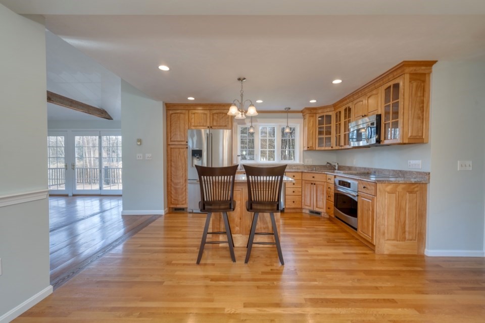 21 Strawberry Lane Whitman, MA 02382 - Photo 15 of 39 a open kitchen with stainless steel appliances granite countertop a stove top oven a sink dishwasher a dining table and chairs with wooden floor