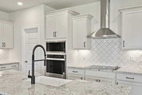 a kitchen with granite countertop white cabinets and stainless steel appliances