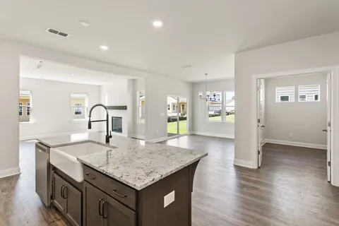 a kitchen with granite countertop kitchen island a sink appliances and wooden floor