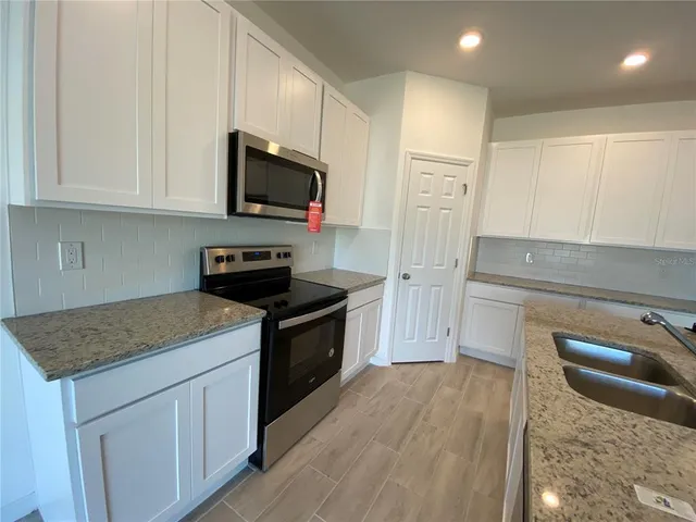 a kitchen with stainless steel appliances granite countertop a stove a sink and a microwave