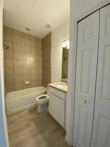 a bathroom with a granite countertop bathtub shower sink vanity and toilet