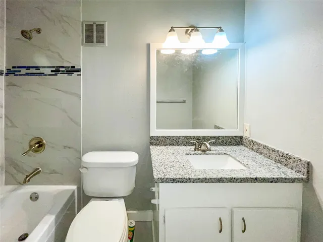 a bathroom with a granite countertop sink toilet and shower