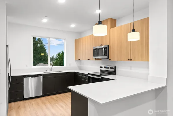 a kitchen with stainless steel appliances a stove a sink and white cabinets with wooden floor