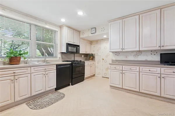 a kitchen with granite countertop white cabinets white appliances a sink and a window