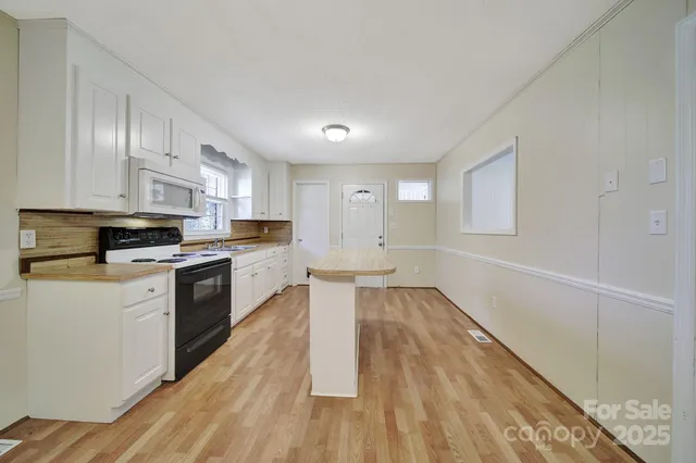 a kitchen with granite countertop a stove top oven a sink dishwasher and a refrigerator with wooden floor