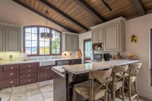 a kitchen with stainless steel appliances kitchen island granite countertop a table chairs sink and cabinets
