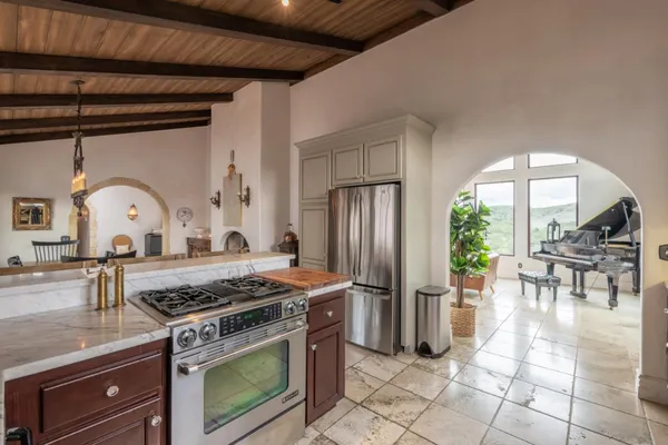 a kitchen with stainless steel appliances granite countertop a stove a refrigerator a dining table and chairs with the living room view